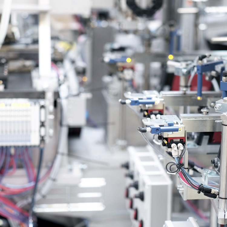 Nærbillede af industriel automatisering, der viser komplicerede maskiner, ledninger og robotkomponenter på en produktionslinje.